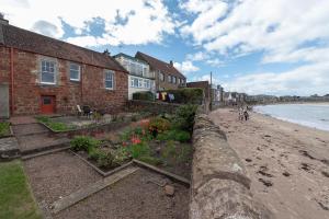 a row of houses on a beach next to the ocean at Beresford Cottage in North Berwick