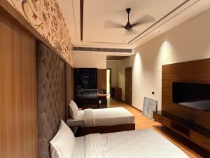 a hotel room with two beds and a flat screen tv at City Center Suites in Bhatinda