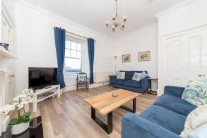 a living room with a blue couch and a table at Beresford Cottage in North Berwick