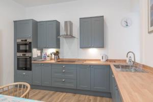 a kitchen with blue cabinets and a wooden floor at Beresford Cottage in North Berwick