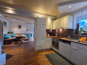 a kitchen with white cabinets and a dining room at Feines Alpennest in Hopfgarten im Brixental