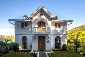 a white house with a door and a balcony at Winterbourne Chalet in Coonoor