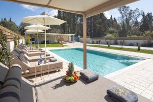 a swimming pool with lounge chairs and an umbrella at Villa Kouros P&A in Áfra