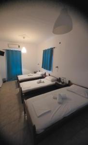a row of beds in a room with blue curtains at Pension Panagiota in Spetses +31 photos