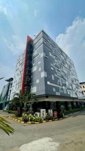 a large gray building with palm trees in front of it at StarRay Hotel Jakarta Mangga Dua Square in Jakarta