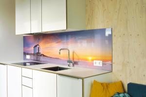 a kitchen with a sink and a painting of a lighthouse at Noardewyn - Ecohuisjes Terschelling in Midsland