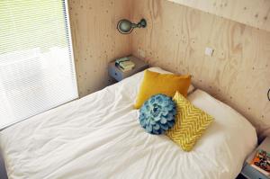a bedroom with a bed with yellow and blue pillows at Noardewyn - Ecohuisjes Terschelling in Midsland +10 photos
