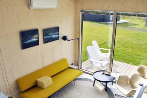 a living room with a yellow couch and chairs at Noardewyn - Ecohuisjes Terschelling in Midsland