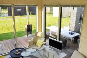 a living room with a screened in porch with a television at Noardewyn - Ecohuisjes Terschelling in Midsland