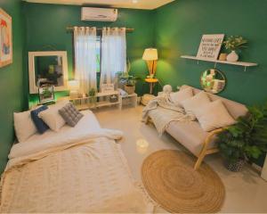 a living room with green walls and a couch at Greeny garden house in Ban Na Sat