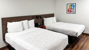 a hotel room with two beds with white sheets at Motel 6 Classic Galveston, TX Beach-Seawall in Galveston +23 photos