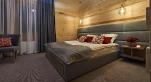 a bedroom with a large bed and a chair at Tatrzański Bór Apartamenty in Małe Ciche