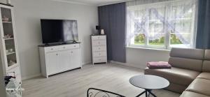 a living room with a couch and a flat screen tv at Ferienwohnung am Waldrand 1 in Stary Przybsław
