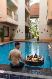 a man sitting in front of a swimming pool with a tray of food at Victor Exotica An Indy Resort in Candolim