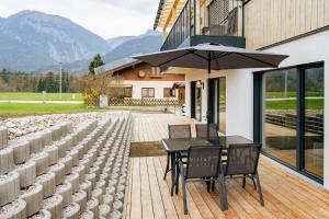 a patio with a table and chairs and an umbrella at Wiesenblick Residences - by myNests in Haus im Ennstal