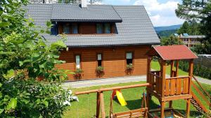 a wooden house with a playground in front of it at Solińskie Podgórze in Solina