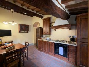 a kitchen with wooden cabinets and a table and a dining room at Le Torri View Apartment - San Gimignano in San Gimignano