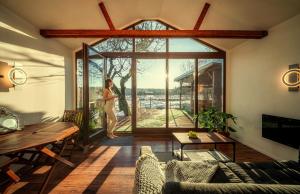a woman standing in a living room with a large window at Pillanat Wellness Kabin in Bánk