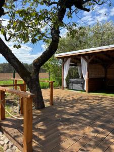 a wooden deck with a tree and a pavilion at Pillanat Wellness Kabin in Bánk +2 photos