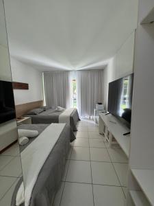 a hotel room with two beds and a flat screen tv at Iloa Residence V13 Beach - localização privilegiada in Barra de São Miguel