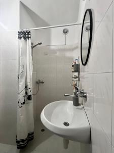 een witte badkamer met een wastafel en een spiegel bij Modern flat near downtown Plovdiv in Plovdiv +29 foto's