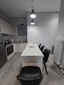 a kitchen with a white counter and black chairs at SeDi Cozy Apartment in Chios