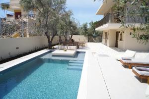 a swimming pool with lounge chairs and a house at Villa Noema Kineta in Kineta