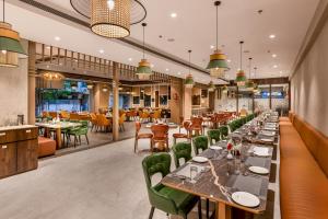 a restaurant with long tables and green chairs at SkkyLight Lords Inn Nanded in Nānded