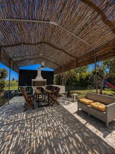 eine Terrasse mit Tisch und Stühlen unter einem Strohdach in der Unterkunft Enervillas 2030 in Káto Achaḯa