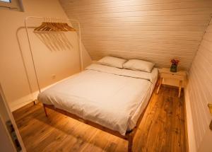 a small bed in a room with a wooden floor at Kamonkő Panoráma Kuckó in Szigliget