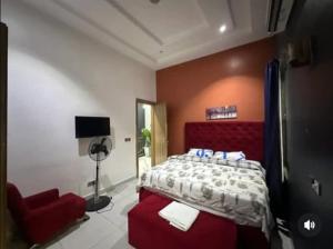 a bedroom with a bed and a red chair at Jolie Homes in Lekki