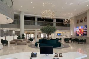 eine Lobby mit einer grünen Couch sowie Tischen und Stühlen in der Unterkunft Crowne Plaza Riyadh Palace by IHG in Riad