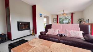a living room with a brown leather couch and a fireplace at Les Ptis Bregeons in Talmont