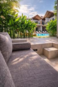 a couch sitting in front of a house with a pool at Bella Vida Resort, Uluwatu in Uluwatu