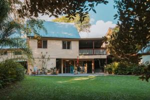 a wooden house with a porch and a yard at Glasshouse Mountains Ecolodge in Glass House Mountains