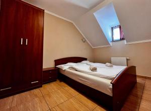 a bedroom with a bed and a wooden cabinet at Kolbászház Apartman in Gyula