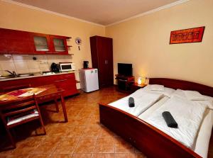 a bedroom with a bed and a table and a kitchen at Kolbászház Apartman in Gyula +31 photos