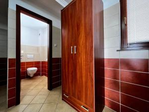 a bathroom with a wooden door and a toilet at Kolbászház Apartman in Gyula