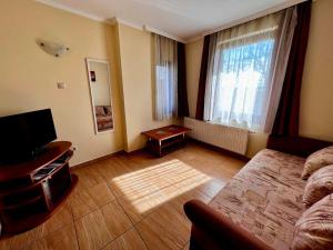 a bedroom with a bed and a television and a window at Kolbászház Apartman in Gyula