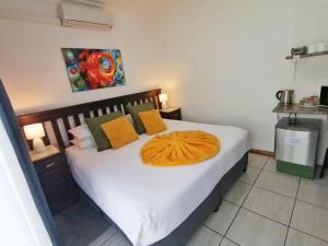 a bedroom with a bed with white sheets and yellow pillows at Sleep@161 Benade Drive in Bloemfontein