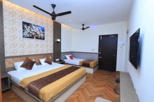 a hotel room with two beds and a tv at Thendral inn in Vellore