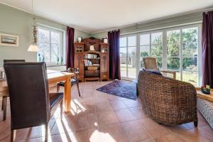 a dining room with a table and chairs and windows at Haus Arrewind in Ahrenshoop