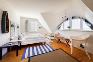 a white room with a bed and a table and chairs at Haus Arrewind in Ahrenshoop