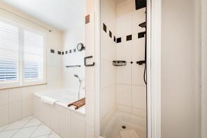 a white bathroom with a tub and a shower at Haus Arrewind in Ahrenshoop