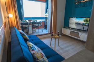 a living room with a blue couch and a tv at L'Horizon Bleu - Vue Etang - Parking - Plage à 5 min in Le Barcarès