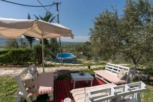 a patio with an umbrella and a table and chairs at Bujtina Ethan Perondi - Private Villa Swimming Pool in Kuçovë