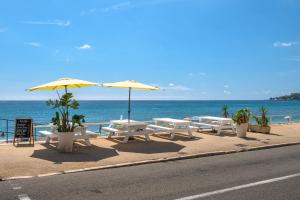 a row of picnic tables and umbrellas on the beach at Le Coq Elysium - Exceptional 220 sqm Penthouse - Private Terrace & Jacuzzi - AC - 3 Parking Spaces in Menton