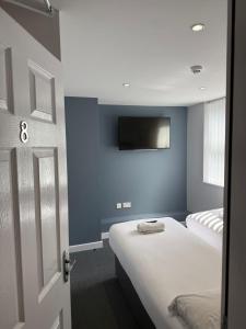 a room with two beds and a tv on the wall at Brownlows Inn Rooms formerly Riley's Rooms in Liverpool +7 photos