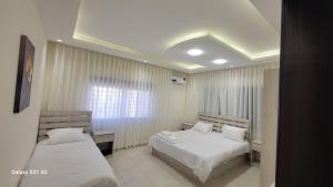a bedroom with two beds and a window at #302 brand new two large bedrooms in Rujm ash Sharāʼirah