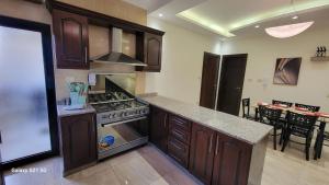 a kitchen with wooden cabinets and a stove top oven at #302 brand new two large bedrooms in Rujm ash Sharāʼirah